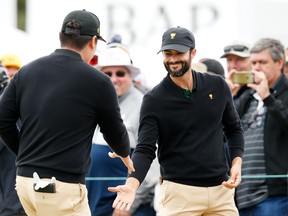 Internationals Adam Hadwin of Canada (right) and Sungjae Im of South Korea celebrate after defeating Xander Schauffele and Patrick Cantlay of the U.S. team during four-ball matches at the Presidents Cup at Royal Melbourne Golf Course. (Getty Images)