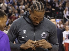 Former Raptors MVP Kawhi Leonard accepts his NBA Championship ring from former teammate Kyle Lowry before the Raptors-Clippers game on Wednesday. STAN BEHAL/TORONTO SUN