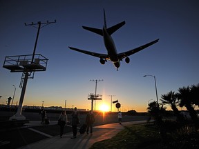 Passengers pull their luggage outside Los Angeles International Airport (LAX) as a plane comes in for a landing at dusk November 1, 2013 in Los Angeles. (ROBYN BECK/AFP/Getty Images)