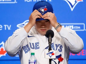 Toronto Blue Jays newly signed pitcher Hyun-Jin Ryu fixes his hat after putting on his Toronto Blue Jays uniform for the first time at a press conference announcing his signing to the team, in Toronto, Friday, Dec. 27, 2019.