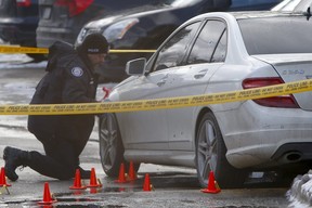 Toronto Police officers collect evidence, believed to be empty shell casings, next to a bullet-riddled Mercedes Benz after a man was shot at a TCHC townhouse complex at 210 Duncanwoods Dr. on Thursday, Dec. 5, 2019. (Chris Doucette/Toronto Sun)