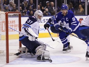 Jets goaltender Connor Hellebuyck blocks a shot as Leafs forward John Tavares looks for the rebound last night. (USA TODAY SPORTS)