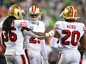 Richard Sherman of the San Francisco 49ers, center, and Marcell Harris, left, and Jimmie Ward talk things out during a timeout in the fourth quarter of the game against the Seattle Seahawks at CenturyLink Field on December 29, 2019 in Seattle, Washington.