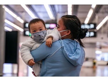 *** BESTPIX *** HONG KONG, CHINA - JANUARY 29: A woman carries a baby wearing a protective mask as they exit the arrival hall at Hong Kong High Speed Rail Station on January 29, 2020 in Hong Kong, China. Hong Kong government will deny entry for travellers who has been to Hubei province except for local residents in response to tighten the international travel and border crossing to stop the spread of the virus.