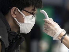 A passenger receives a temperature check before taking a flight bound for Wuhan at Spring Airlines' check-in counter at Haneda airport on January 31, 2020 in Tokyo, Japan.