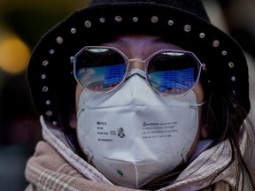 The departure gates board is reflected on the shades of a passenger wearing a protective mask as she travels for the Lunar New Year holidays, at the Beijing West Railway Station in Beijing on Jan. 24, 2020. (AFP via Getty Images)