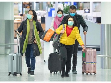 Flight passengers wear face masks at a check-in of Chinese airline Air China on January 30, 2020 at the airport in Frankfurt am Main, western Germany. - Germany's flagship carrier Lufthansa said on January 29, 2020 it was cancelling all flights to mainland China until February 9, 2020, as fears mount over the deadly coronavirus. (Photo by Boris Roessler / dpa / AFP) / Germany OUT