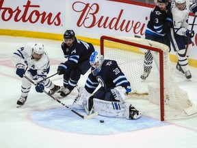 Winnipeg Jets goalie Laurent Brossoit (30) makes a save on a shot by Maple Leafs forward Auston Mathews (34) during the third period at Bell MTS Place on Thursday.Terrence Lee-USA TODAY Sports ORG