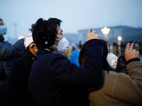 People wearing face masks use their cellphones at the Tiananmen Square, as the country is hit by an outbreak of the new coronavirus, in Beijing, China January 27, 2020.
