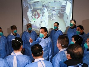 Chinese Premier Li Keqiang wears a mask and protective suit while speaking to medical workers during a visit to Jinyintan hospital in Wuhan, China on Monday
