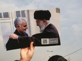 A man holds a picture of Iran's supreme leader Ayatollah Ali Khamenai with Iranian Revolutionary Guards top commander Qassem Soleimani (L) during a demonstration in Tehran on January 3, 2020 against the killing of the top commander in a US strike in Baghdad.  (Photo by ATTA KENARE/AFP via Getty Images)