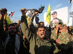 Members of the Hashed al-Shaabi paramilitary force chant anti-U.S. slogans during a protest over the killings of Iranian commander Qassem Soleimani and Iraqi paramilitary commander Abu Mahdi Al-Muhandis, on January 6, 2020 in Karrada in central Baghdad. (Photo by AHMAD AL-RUBAYE / AFP)
