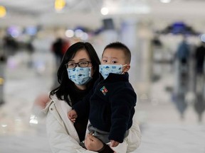 A woman and a child wearing protective masks walk toward check-in counters at Daxing international airport in Beijing on January 21, 2020.