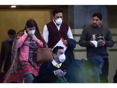 People wearing protective facemasks walk out from a Pakistan-based Chinese company in Islamabad on January 30, 2020, after instructions from Pakistani authorities to take preventive measures against the coronavirus. - A virus similar to the SARS pathogen has killed 170 people and spread around the world since emerging in a market in the central Chinese city of Wuhan. (Photo by Aamir QURESHI / AFP)