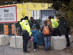A family, claiming to be from Columbia, is arrested by RCMP officers as they cross the border into Canada from the United States as asylum seekers, on April 18, 2018, near Champlain, N.Y. (THE CANADIAN PRESS/Paul Chiasson)