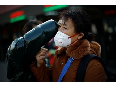 A woman gets help to fit her face mask outside Beijing Railway Station as the country is hit by an outbreak of the new coronavirus, in Beijing, China January 30, 2020. REUTERS/Carlos Garcia Rawlins ORG XMIT: CH015