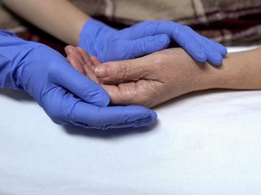 A nurse holds a patient's hand.