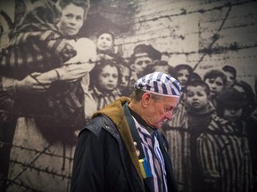 Ukrainian Holocaust survivor Igor Malitski walks past a picture in one of the barracks at the former Auschwitz concentration camp in Oswiecim on January 26, 2015. Survivors and heads of state will attend a ceremony marking the 70th anniversary of the liberation of the camp by Soviet troops on January 27, 1945.   AFP PHOTO / ODD ANDERSEN        (Photo credit should read ODD ANDERSEN/AFP via Getty Images)