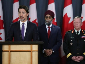Minister of National Denfence Harjit Sajjan (C) and Chief of Defence Staff General Jonathan Vance (R) listen as Canadian Prime Minister Justin Trudeau (L) speaks during a news conference January 9, 2020 in Ottawa. (Photo by Dave Chan / AFP)