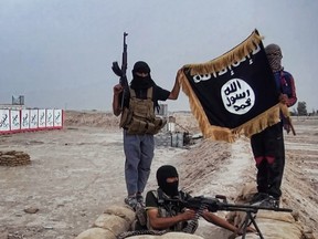 In this file photo taken on June 11, 2014, an image made available on the jihadist website Welayat Salahuddin shows militants of the Islamic State of Iraq and the Levant (ISIL) posing with the trademark Jihadists flag after they allegedly seized an Iraqi army checkpoint in the northern Iraqi province of Salahuddin.
