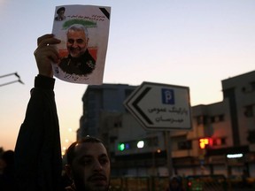 A man holds a picture of late Iranian Major-General Qassem Soleimani, as people celebrate in the street after Iran launched missiles at U.S.-led forces in Iraq, in Tehran, Iran January 8, 2020.
