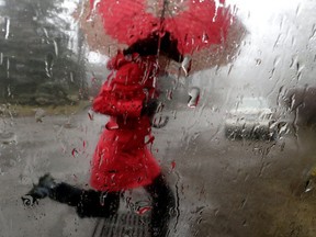 File photo of a woman jumping over a puddle during a dreary day in Toronto on Sunday, Jan. 10, 2016. (Craig Robertson/Toronto Sun/Postmedia Network)