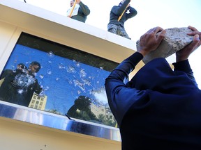 A protester holds a rock to break a glass window of a security guard building of the U.S. Embassy, as people gather to condemn air strikes on bases belonging to Hashd al-Shaabi (paramilitary forces), in Baghdad, Iraq Dec. 31, 2019.