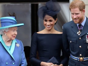 From left: Queen Elizabeth II, Meghan, Duchess of Sussex, and Prince Harry, Duke of Sussex watch the RAF flypast on the balcony of Buckingham Palace, as members of the Royal Family attend events to mark the centenary of the RAF on July 10, 2018 in London, England.