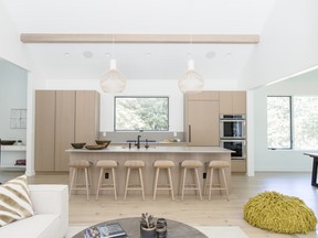 The light-filled kitchen features custom cabinetry in white oak and an island of Caesarstone and raw concrete.