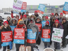 Elementary teachers pose for a group photo in the freezing rain outside Molly Brant Elementary School in Kingston, Ont. on Thursday, Feb. 6, 2020, during the provincewide Elementary Teachers' Federation of Ontario labour strike.