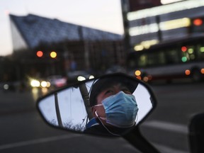 A Chinese man is seen in the side mirror of his scooter as he wears a protective mask while waiting at a red light on Feb. 22, 2020 in Beijing. (Kevin Frayer/Getty Images)