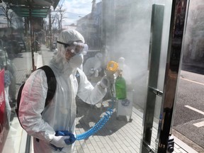 Disinfection professionals wearing protective gear spray antiseptic solution against the coronavirus (COVID-19) on Thursday in Seoul, South Korea.