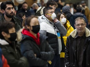People wear masks as they wait for arrivals at Pearson International Airport on Jan. 25, 2020. (The Canadian Press)
