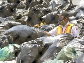 A pest-control worker sprays bags of trash at a temporary dump set up at Christie Pits during a garbage strike in July 2009. (Toronto Sun files)