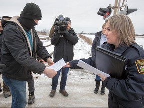 A court injunction is presented to members of the Mohawk Territory as they block the CN/VIA train tracks in Tyendinaga Mohawk Territory, near Belleville, Ont., on Tuesday, Feb. 11, 2020, in support of Wet'suwet'en's blockade of natural gas pipeline in northern B.C. THE CANADIAN PRESS/Lars Hagberg