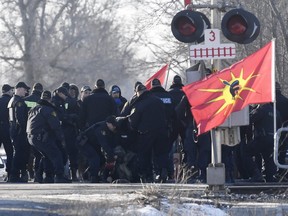 Ontario Provincial Police officers make an arrest at a rail blockade in Tyendinaga Mohawk Territory, near Belleville, Ont., on Monday Feb. 24, 2020, as they protest in solidarity with Wet'suwet'en Nation hereditary chiefs attempting to halt construction of a natural gas pipeline on their traditional territories. THE CANADIAN PRESS/Adrian Wyld