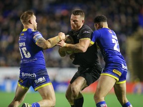 The Toronto Wolfpack's Adam Sidlow is tackled by two Warrington Wolves during Friday's game. (Stephen Gaunt/Touchlinepics.com)