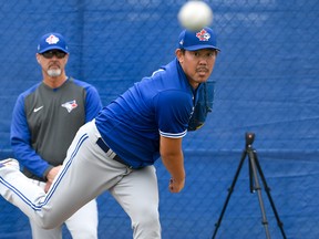 Japanese import Shun Yamaguchi warms up under the watchful eye of pitching coach Pete Walker during early Blue Jays spring training workouts yesterday at Spectrum Field in Dunedin.  Douglas DeFelice/USA TODAY
