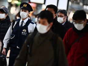 Mask-clad commuters make their way to work during morning rush hour at the Shinagawa train station in Tokyo on February 28, 2020. (CHARLY TRIBALLEAU/AFP via Getty Images)