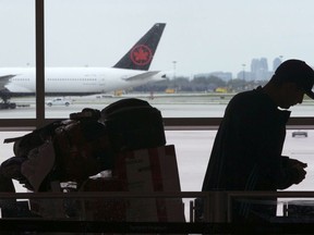 A passenger waits beside their luggage at the departure terminal at Toronto Pearson Airport, in Mississauga, Ont., Friday, May 24, 2019.