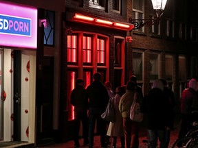 People walk past a brothel in the red light district of Amsterdam, Netherlands, on April 3, 2019.