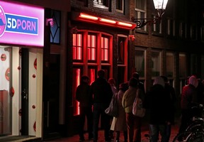 People walk past a brothel in the red light district of Amsterdam, Netherlands, on April 3, 2019. Files