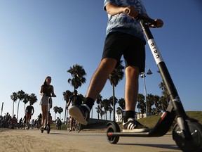 In this Aug. 13, 2018, file photo, People ride Bird shared dockless electric scooters along Venice Beach in Los Angeles.