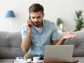 Angry man talking on phone disputing over computer laptop problem