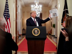 U.S. President Donald Trump holds up a copy of the Washington Post's front page showing news of Trump's acquittal in his Senate impeachment trial, as he delivers a statement about his acquittal in the East Room of the White House in Washington, U.S., February 6, 2020.
