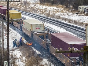 As a train moves through Tyendinaga on Wednesday, Feb. 26, 2020, protesters light wooden pallets on fire next to the tracks while police look on from the other side.