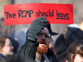 A supporter of the indigenous Wet'suwet'en Nation holds a sign before a march, as part of a protest against British Columbia's Coastal GasLink pipeline, in Toronto February 17, 2020. (REUTERS/Chris Helgren)