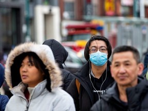 A man wearing a mask walks in the Chinatown district of downtown Toronto, Ontario, after 3 patients with novel coronavirus were reported in Canada January 28, 2020. REUTERS/Carlos Osorio ORG XMIT: GGG-TOR112