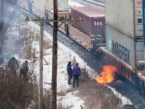 A fire burns next to a passing CN Rail train beside an encampment of the Tyendinaga Mohawk Territory, set up in support of the Wet'suwet'en Nation who are trying to stop construction of British Columbia's Coastal GasLink pipeline, on Feb. 26, 2020. (REUTERS/Alex Filipe)