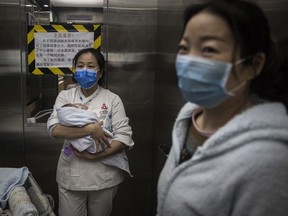 Maternity nurses wears a mask as she cares for a newborn at a Private maternity hospital on March 12, 2020 in Wuhan, Hubei, China.